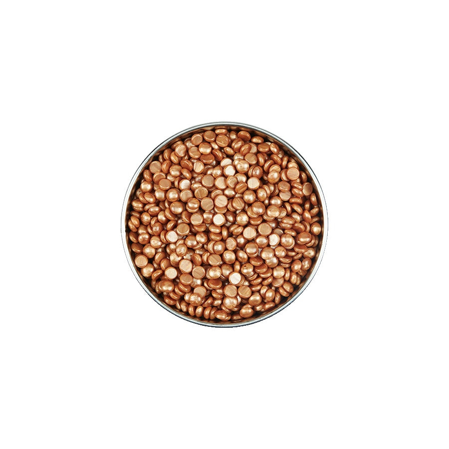 Metallic gold beads in a round container on a white background