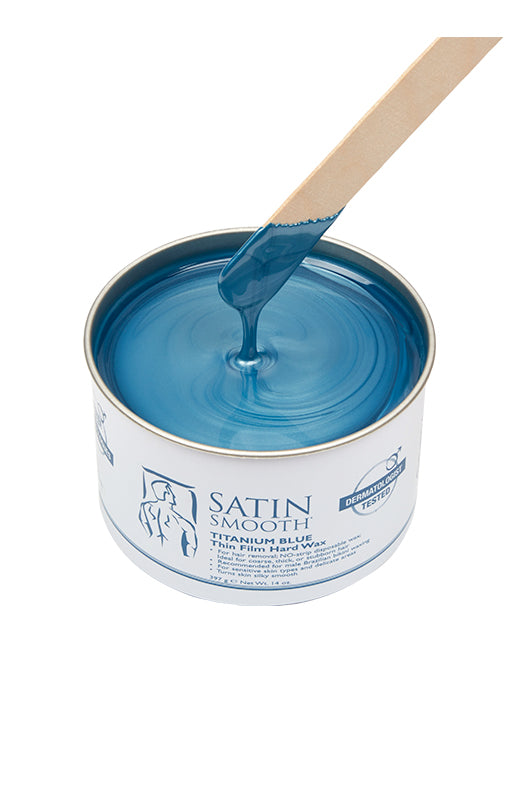 Dripping wax stick dipped into open can of Satin Smooth Titanium Blue Thin Film Hard Wax showing its color & texture