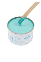 Dripping wax stick dipped into open can of Satin Smooth Tea Tree Wax showing its full creamy light green color & texture